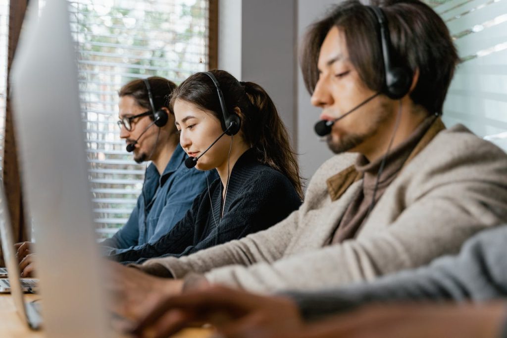 Three call center agents working diligently with headsets in an office setting, showcasing teamwork.